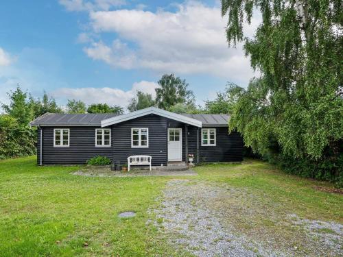 a black house with a bench in a yard at Cozy holiday home in Asserbo in Helsinge