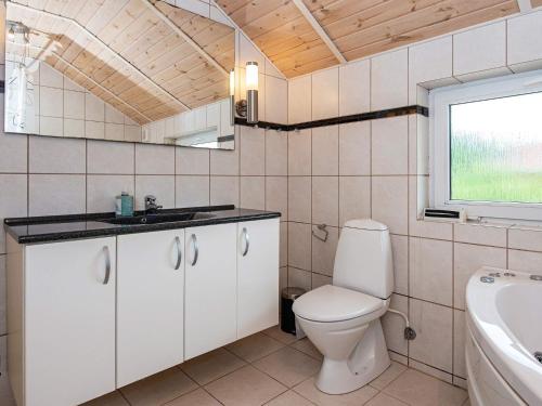 a bathroom with a toilet and a sink and a window at Holiday home Oksbøl LXXXIII in Oksbøl
