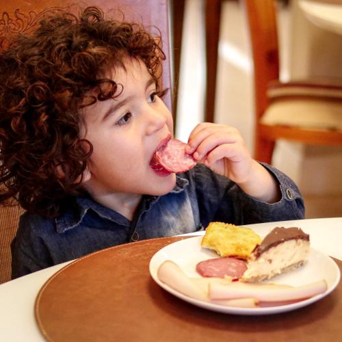 a young child sitting at a table eating a plate of food at Hotel Gramado Interlaken in Gramado