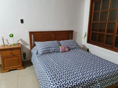 a bed with a blue and white comforter in a bedroom at Uriburu B&B in Resistencia