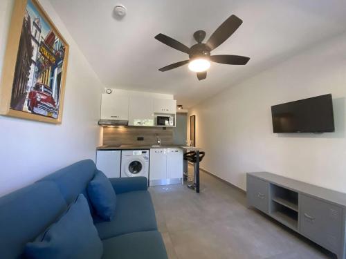 - un salon avec un canapé bleu et un ventilateur de plafond dans l'établissement Studio climatisé avec terrasse, piscine et parking sécurisé - Les Issambres (83), 2 couchages - FR-1-226-494, à Saint-Peïre-sur-Mer