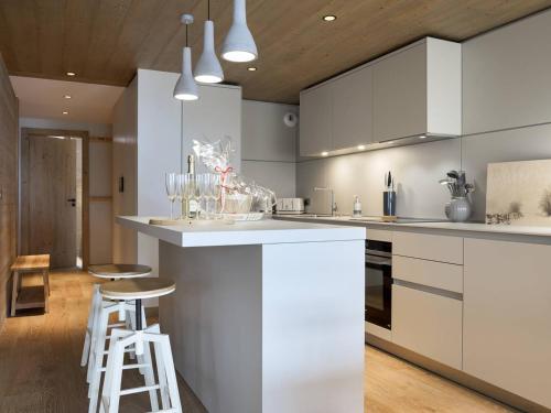 une cuisine avec des placards blancs et un bar avec des tabourets dans l'établissement Appartement 96m² - 8 pers - Courchevel Village - Centre station & à côté des pistes - Balcon - SPA - FR-1-631-104, à Courchevel