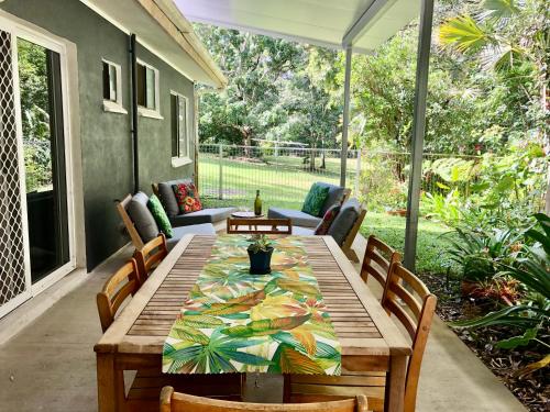 a wooden table on a patio with chairs at Honeybee House in Kuranda