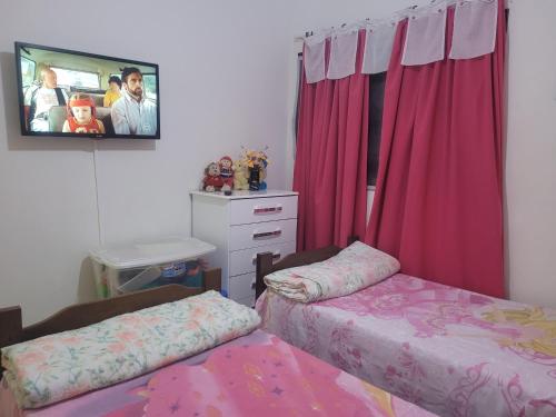 1 Schlafzimmer mit 2 Betten und einem TV an der Wand in der Unterkunft Apartamentos em Olímpia próximos Thermas dos laranjais in Olímpia