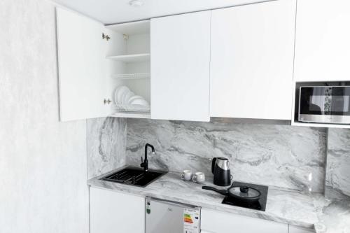 a white kitchen with white cabinets and a sink at Люкс 1 комнатная in Rudny