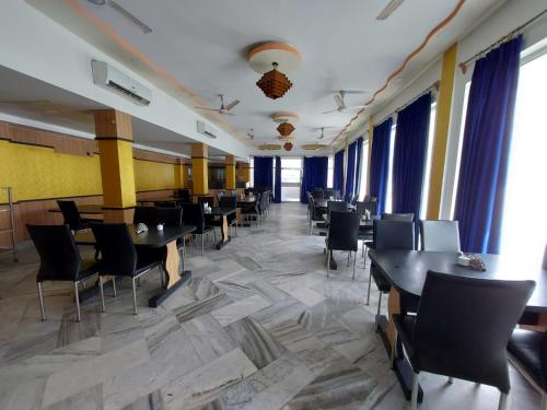 ein Esszimmer mit Tischen und Stühlen und Fenstern in der Unterkunft Hotel Sea Coast in Digha