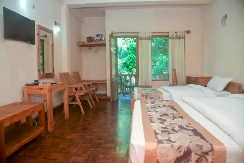 a hotel room with two beds and a table and chairs at Chitwan Paradise Hotel in Sauraha