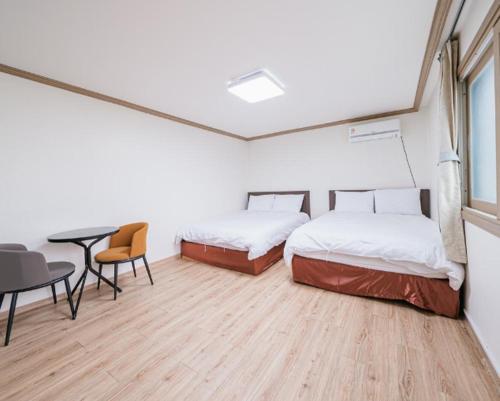 two beds in a room with a table and chairs at Top Island Hotel in Jeju