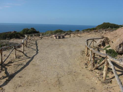 a dirt road with a fence and the ocean at Hotel Don Pedro in Portoscuso