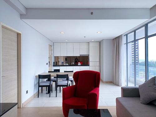a living room with a red chair and a kitchen at Straits Suite by C Homestay Malacca in Malacca