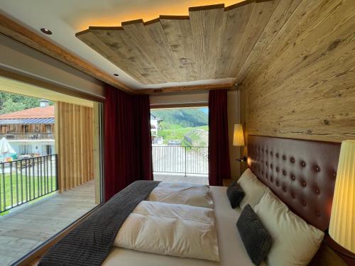 um quarto com uma cama grande e uma janela grande em Villa Anita Chalets em Valle Di Casies
