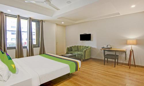 a hotel room with a bed and a chair and a desk at Treebo Ahinsa Residency Sohna Road in Gurgaon
