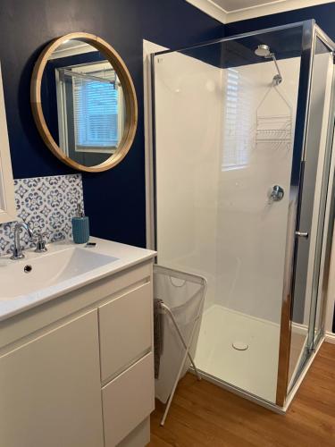a bathroom with a shower and a sink and a mirror at Griffith St Beach House in Port Fairy