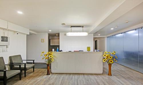 an office with a reception desk and chairs and flowers at Treebo Trend Ahinsa Residency Sohna Road in Gurgaon