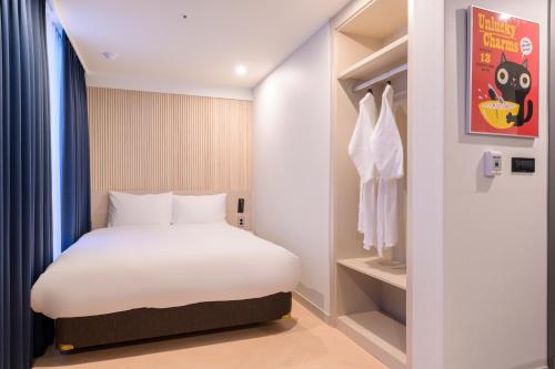 a hotel room with a bed and a dresser at Ventimo Hotel & Residence Jeju in Jeju