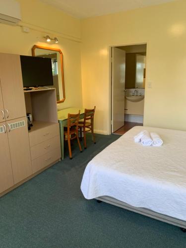 a hotel room with a bed and a desk and a television at Temora Motel in Temora