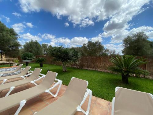 a row of white lounge chairs in a backyard at Finca Sa Canova Agroturismo in Campos