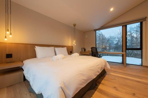 a bedroom with a large bed and a large window at Shion in Kutchan