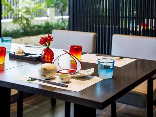 a wooden table with plates and bowls and glasses on it at Hotel Monterey Okinawa Spa & Resort in Onna
