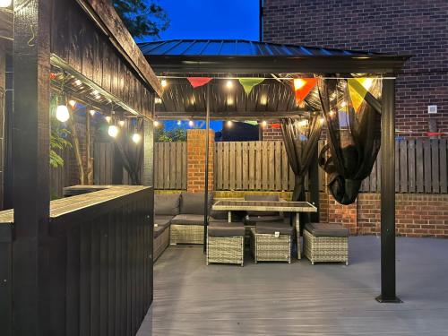 a patio with a table and chairs and lights at Numero Uno Detached Aparthouse in Newcastle upon Tyne