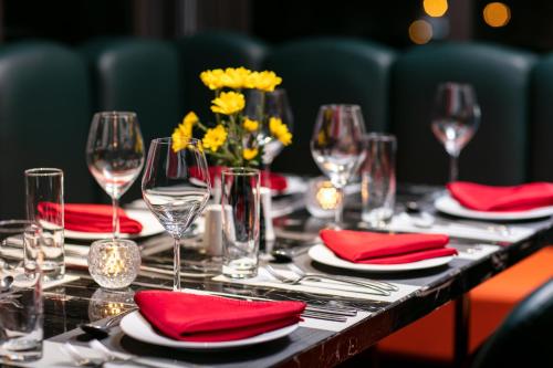 a table with red napkins and wine glasses and flowers at Bendecir Hotel & Spa in Hanoi