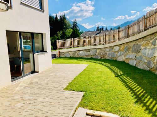 a stone retaining wall next to a yard with a fence at Ferienwohnung Kerschbaumer in Gries am Brenner
