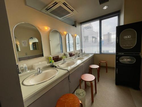 uma casa de banho com dois lavatórios e dois espelhos em カプセル&サウナ日本 -男性専用 men only- em Fukuyama