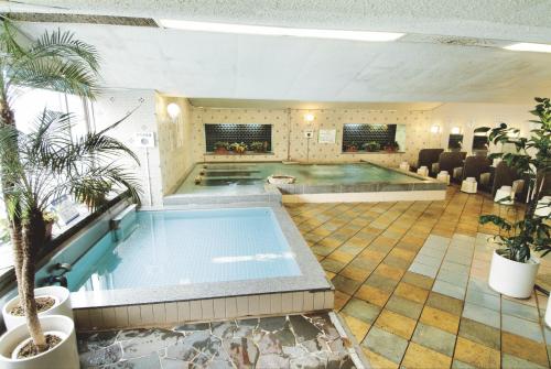 uma grande piscina num grande quarto com cadeiras em カプセル&サウナ日本 -男性専用 men only- em Fukuyama
