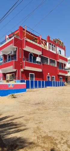 a red building with a blue fence in front of it at Nuba Dool in Aswan