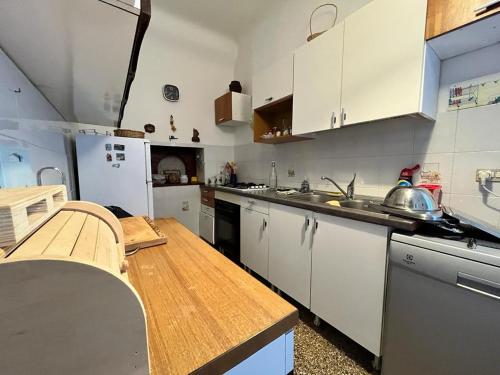 una cucina con armadi bianchi e ripiano in legno di Appartamento in Villa Venezuela piano Terra a Porto di Maratea