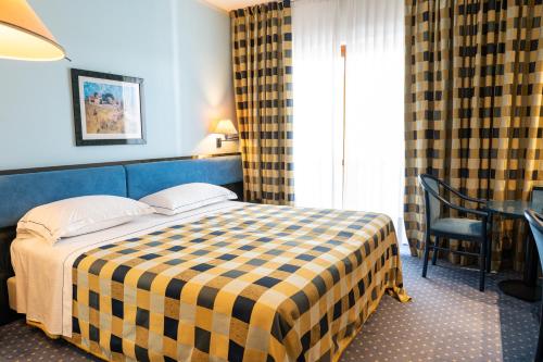 a hotel room with a bed with a checkered blanket at Pizzomunno Vieste Palace Hotel in Vieste