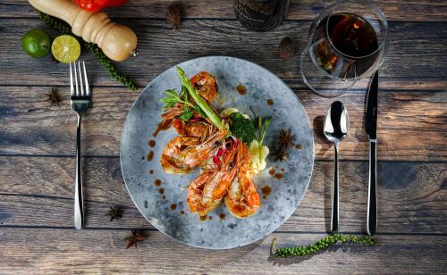 a plate of food on a wooden table with forks at Bendecir Hotel & Spa in Hanoi