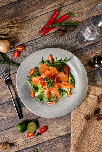 a plate of salad with salmon on a wooden table at Bendecir Hotel & Spa in Hanoi