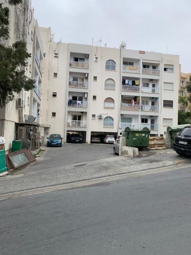 a large white building with cars parked in front of it at White Arches Modern Beautiful studio in Limassol