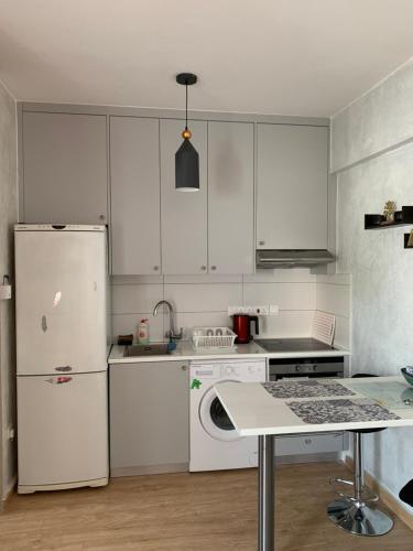 a kitchen with white cabinets and a white refrigerator at White Arches Modern Beautiful studio in Limassol