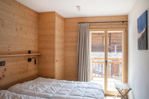 1 dormitorio con paredes de madera, 1 cama y ventana en Polaris appartement 2, en Zinal