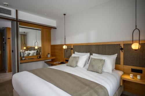 a bedroom with a large white bed with two pillows at Stella Palace Aqua Park Resort in Hersonissos