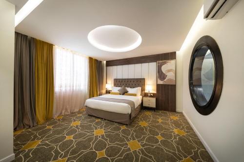 a hotel room with a bed and a mirror at Ahad Rafidah Garden Millennium Hotel in Khamis Mushayt