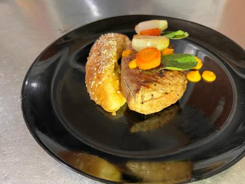 a black plate with a piece of meat and vegetables at Hotel Antika in Peje