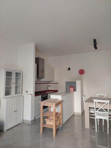 a kitchen with white cabinets and a table and chairs at APPARTAMENTO CALETTA 2 in Castiglioncello