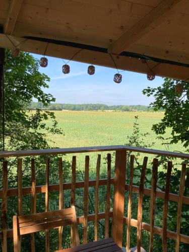 a view of a field from a porch with a bench at Cabanes de la Grande Noe in Les Épasses