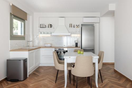 a kitchen with a white table and chairs and a refrigerator at Helia All Seasons Apartments in Astris