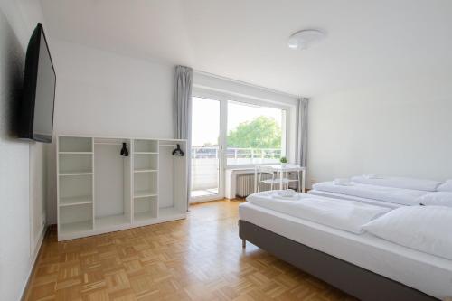 a white bedroom with two beds and a window at Tolstov Apartments - 1 or 3 Room Apartments with Balcony - 20 Min Messe DUS & Airport DUS in Meerbusch