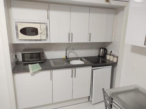 a small kitchen with a microwave and a sink at El Mirador, Villamartin, Refurbished,cot to hire, WIFI, pool, parking in Villamartin