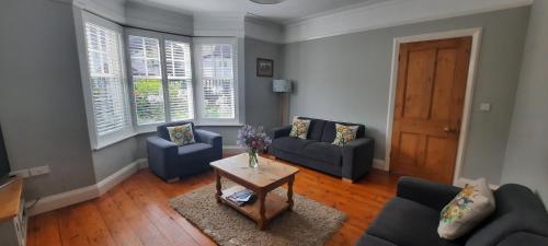 a living room with two blue couches and a table at Dumble Cottage in Minehead