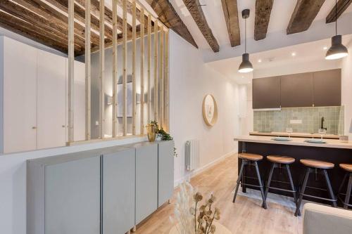 une cuisine avec des armoires blanches et des tabourets de bar dans l'établissement GemBnB Luxury Apartments - Résidence Villedo, à Paris