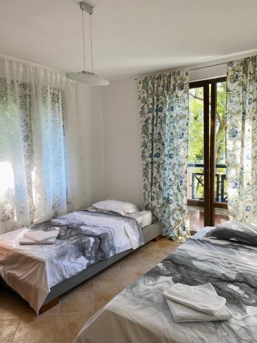two beds in a bedroom with curtains and a window at La Terraza del Oasis in Lozenets