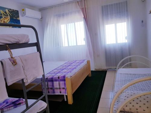 a small room with a bunk bed and two windows at B&B BALANI Rooms in Shkodër