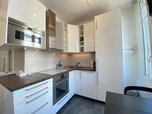 une cuisine blanche avec des armoires blanches et un évier dans l'établissement Studio rénové lumineux proche plage et marché, 4 couchages, balcon, La Baule - FR-1-245-46, à La Baule