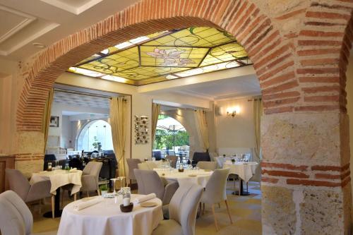 ein Restaurant mit weißen Tischen und Stühlen und einer Buntglasdecke in der Unterkunft Logis Hotels - Château Saint Marcel in Boé